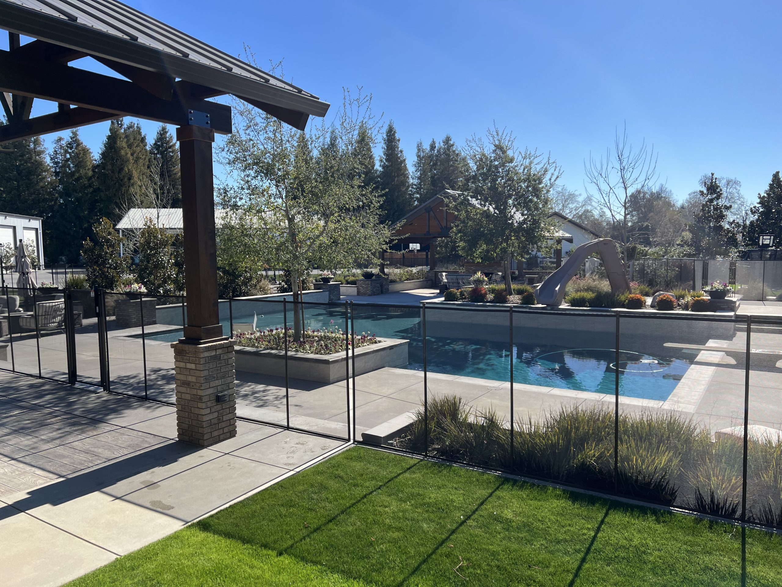 A blue swimming pool sits in a landscaped backyard.