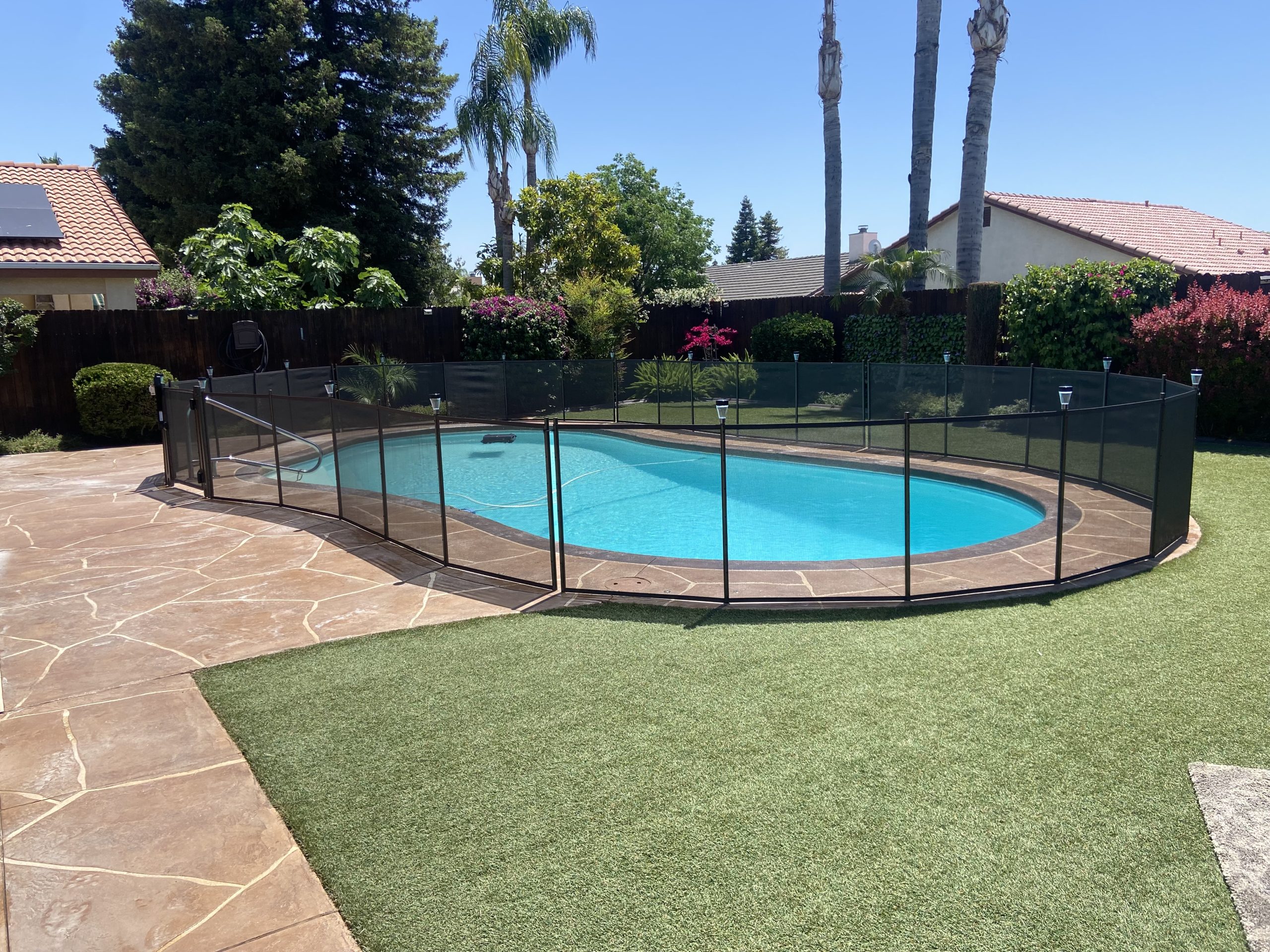 A backyard swimming pool with a stainless steel ladder.